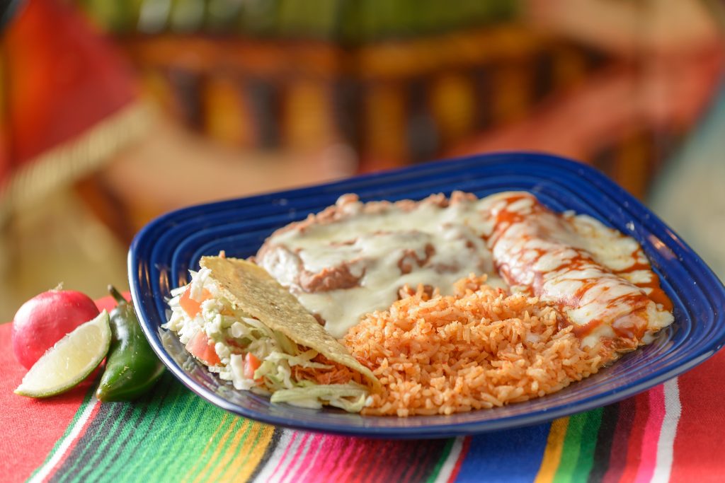 plate with tacos, fried rice, re fried beans, and an enchilada