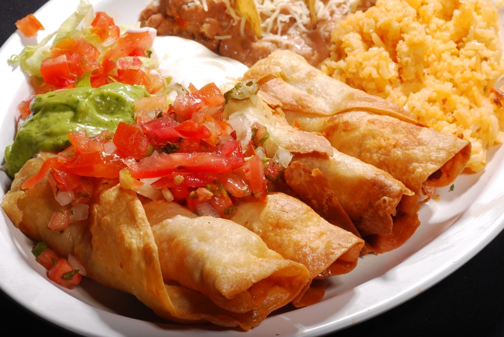 close up of flautas, rice, and beans on a plate