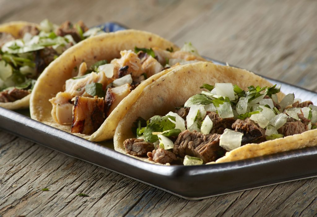 Street tacos on blue plate on wood table