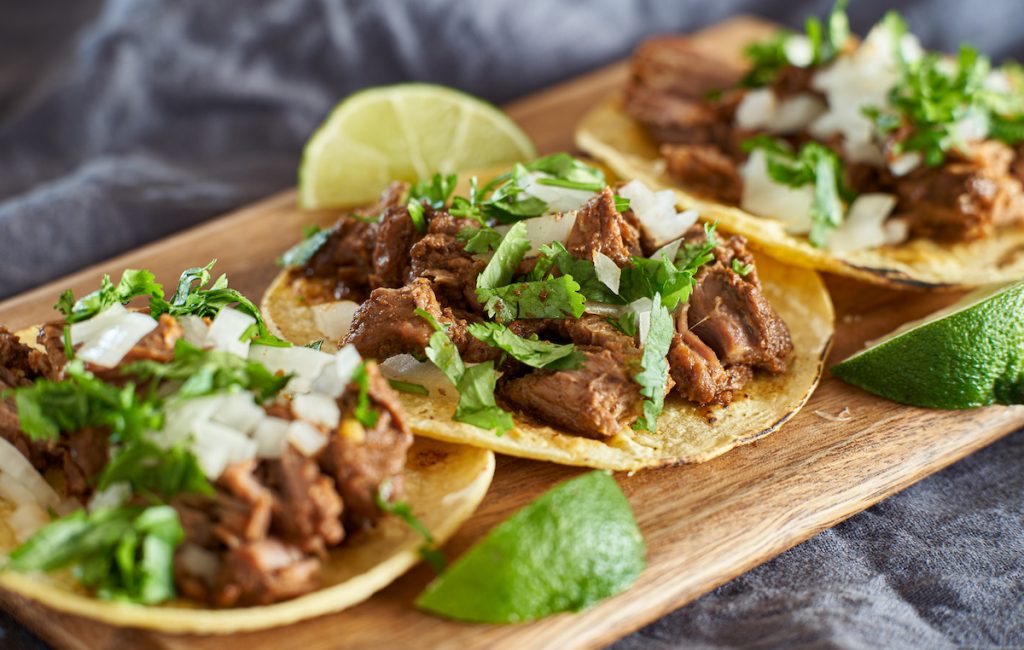 three carne asada mexican street tacos in corn tortilla with lime