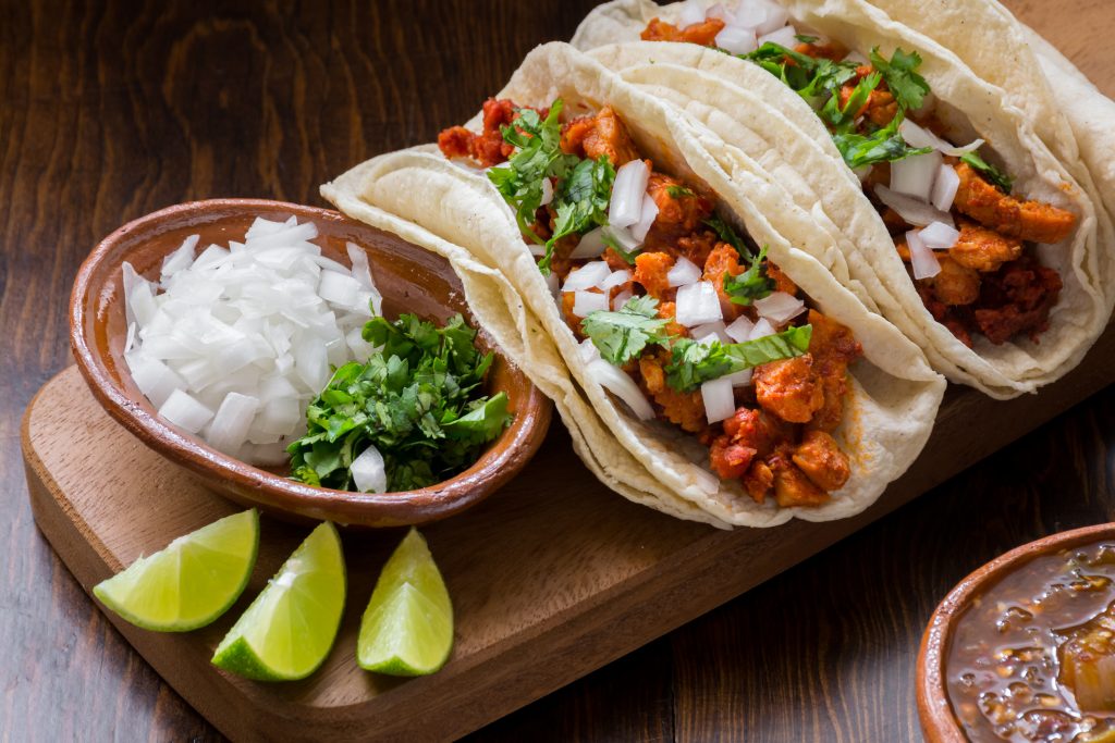 Authentic Mexican tacos with onions, cilantro and lime on wooden surface