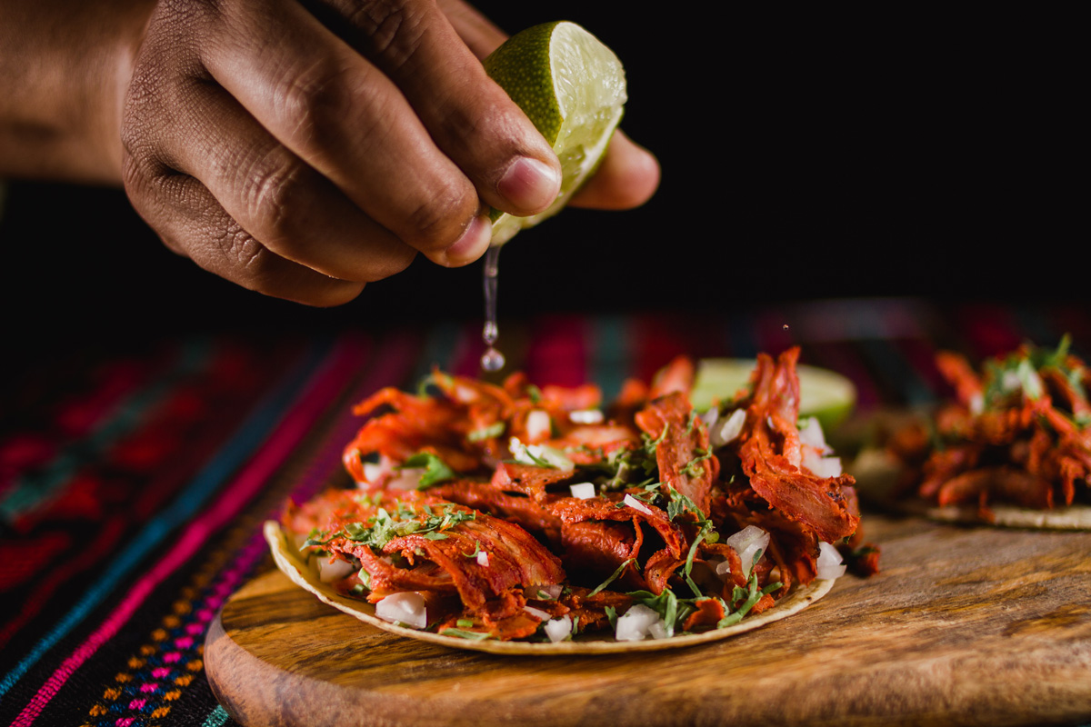 A person’s hand squeezing lime on Mexican meat in El Paso.